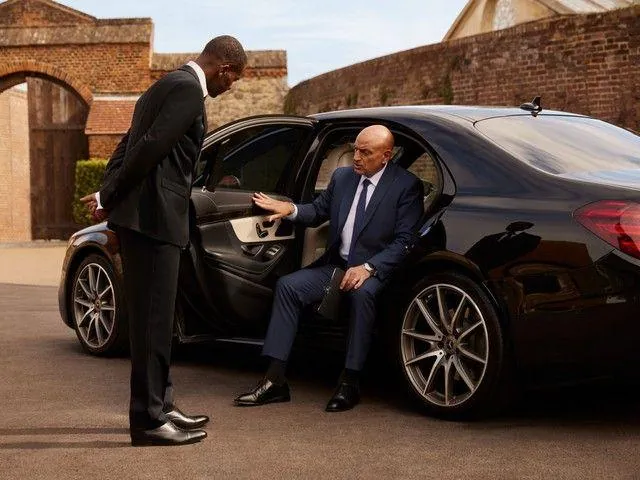 Chauffeur assisting a client into a luxury black car in Dallas–Fort Worth