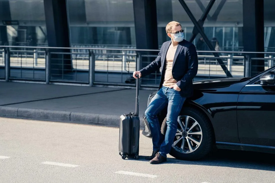 Traveler with luggage beside a black car at DFW Airport